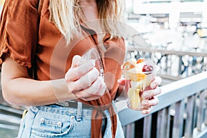 unrecognizable caucasian woman opening a cup of sliced fresh fruits