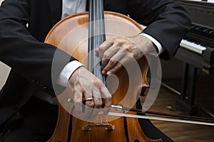 Unrecognizable cellist playing the cello. In the hands of the cellist bow