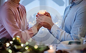 Unrecognizable couple indoors at the table celebrating Christmas.