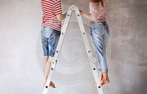 Unrecognizable couple painting walls in their house.