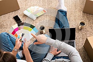 Unrecognizable couple sitting on the floor while woman holding color palette