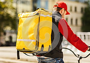 Unrecognizable Courier Delivering Food In Yellow Backpack Riding Bike Outside
