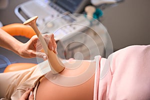 Unrecognizable doctor examines pregnant woman listening to baby& x27;s heartbeat