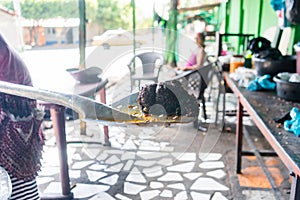 Unrecognizable elderly Nicaraguan woman displaying a piece of blood sausage on a metal ladle