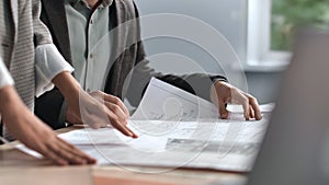 Unrecognizable engineer coworkers plan blueprint architect project brainstorming office desk closeup