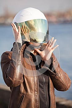 Unrecognizable European woman motorcyclist with white open face helmet with closed mirrored visor