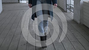 Unrecognizable female in black boots stepping forward. Close up on thin legs