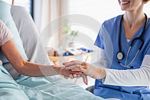 Unrecognizable female doctor examining patient in bed in hospital.