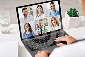 Unrecognizable Female Doctor Using Laptop Computer Communicating With Colleagues Online