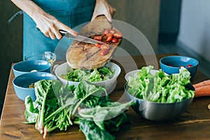 An unrecognizable female hands prepares a salad and puts the ingredients in a large bowl.