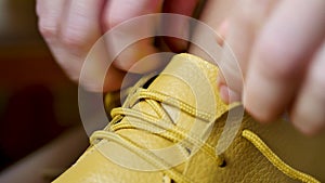 Unrecognizable female person tying shoelaces in yellow footwear
