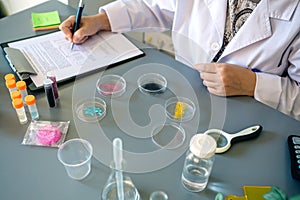 Unrecognizable female scientist examining glitter samples in petri dishes on laboratory