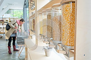 Unrecognizable female shopper in zero waste shop with many bulk dispensers.