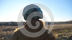 Unrecognizable female soldier of ukrainian army looks at sunset. Back of girl in military uniform and helmet watch at