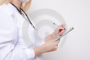 Unrecognizable female woman doctor writing a diagnosis, case medical history on a prescription board