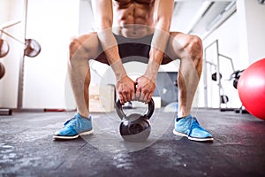 Unrecognizable fit hispanic man in gym working out with kettlebell