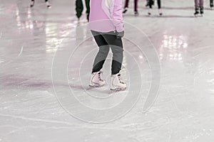 Unrecognizable girl with her back on skates rides on winter Ice rink. Winter activities and sport concept