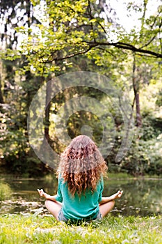 Unrecognizable girl practices yoga in the morning forest.