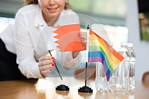 Unrecognizable girl sets midget flags of LGBT and Bahrein before international negotiations photo