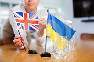 Unrecognizable girl sets midget Ukrainian and Britannic flags before international negotiations photo