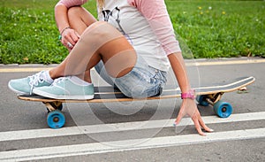 Unrecognizable girl sitting on a longboard