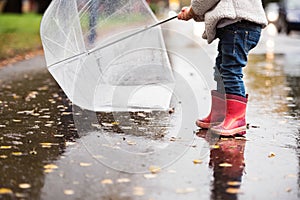 Unrecognizable girl with transparent umbrella on rainy day.