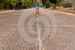 Unrecognizable girl walking in the middle of the street.