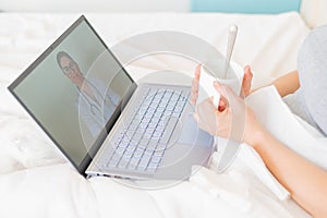 Unrecognizable girl watching a video with medical advice on a laptop. A woman conducts an online conversation with a