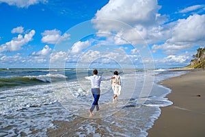 Unrecognizable groom following bride near waving sea