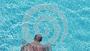 Unrecognizable guy swimming under water in basin at sunny day.