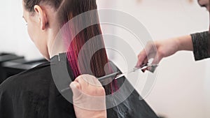 Unrecognizable hairdresser cutting client s red hair