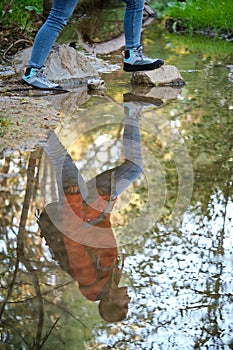 Unrecognizable hiker legs crossing a creek in a forest.