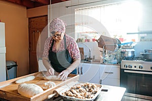 Unrecognizable Latin Elderly Woman Kneading Dough with Hands and Rolling Pin in Her Countryside Kitchen photo