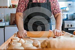 Unrecognizable Hispanic Woman Kneading Dough with Hands and Rolling Pin in Her Countryside Kitchen photo