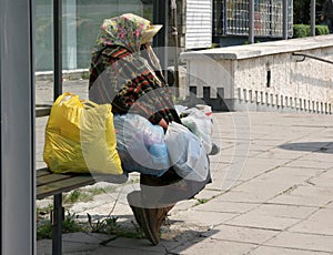 Unrecognizable homeless woman sit on a bus stop. Homeless people. Person in need. Hungry people. Poor person