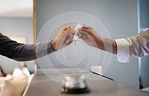 Unrecognizable Hotel Receptionist Giving Key To Guest At Reception, Closeup