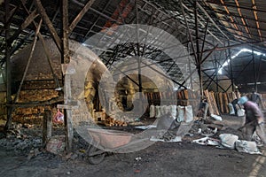 unrecognizable laborers working indoor around the kiln factory.