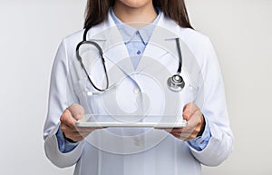 Unrecognizable Lady Doctor Holding Tablet Computer Standing, White Background, Cropped