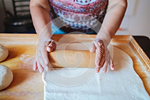 Unrecognizable latin woman kneading dough, cooking homemade bread in her kitchen.