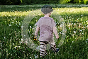 Unrecognizable little boy walking on grass meadow in countryside.