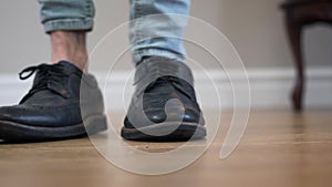 Unrecognizable male Caucasian person standing with legs crossed, stepping aside, turning and leaving. Close-up of men`s