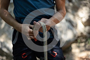 Unrecognizable male climber preparing for climbing by tying the knot