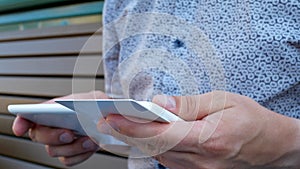 Unrecognizable male person shopping online on bench background outdoor