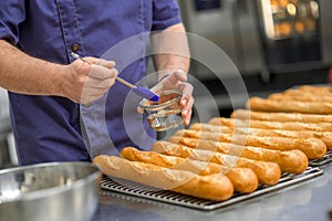 Unrecognizable man baker baking baguettes in bakehouse