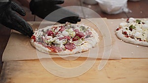 Unrecognizable man in black gloves, pizzaiolo fix raw pizza dough.
