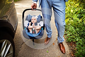 Unrecognizable man carrying his baby girl in a car seat.