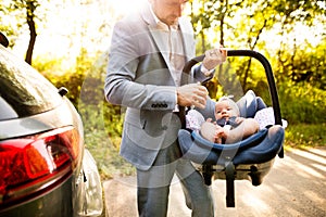 Unrecognizable man carrying his baby girl in a car seat.