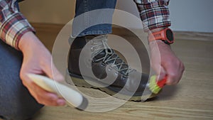 Unrecognizable man cleans brown leather boots with brush and lubricates with cream and blotting protection. Theme shoe