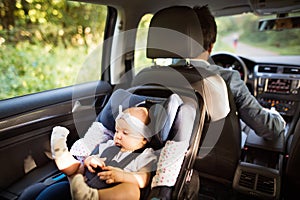 Unrecognizable man driving with a baby girl.