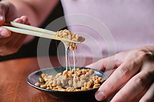 Unrecognizable man eating natto fermented soy beans with chopsticks.